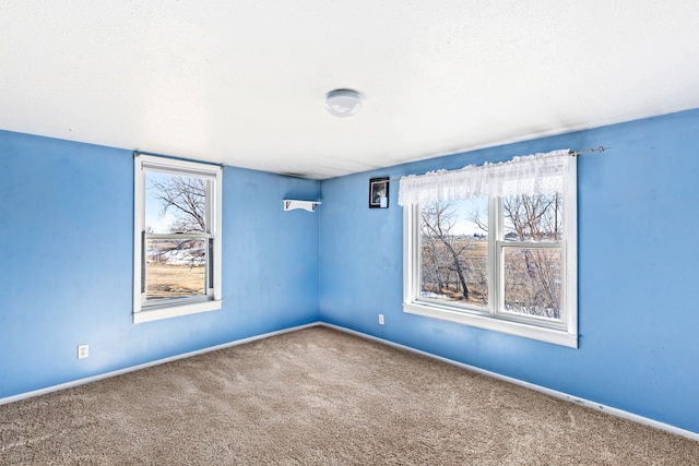 unfurnished room featuring plenty of natural light, baseboards, and carpet flooring