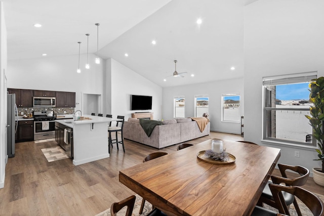 dining space with high vaulted ceiling, recessed lighting, a ceiling fan, and light wood-style floors