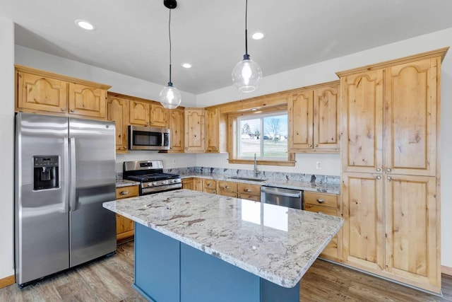 kitchen featuring stainless steel appliances, wood finished floors, a sink, and light stone countertops