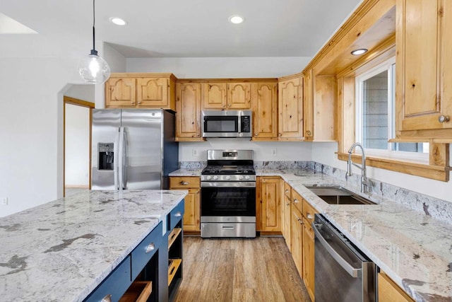 kitchen featuring a sink, light wood-style floors, appliances with stainless steel finishes, light stone countertops, and decorative light fixtures