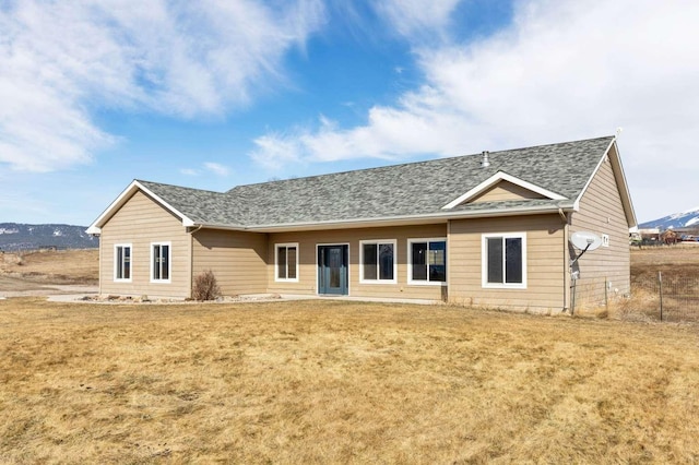 rear view of property featuring a shingled roof and a yard