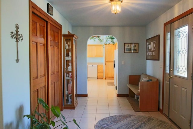 foyer entrance featuring light tile patterned floors, arched walkways, and baseboards