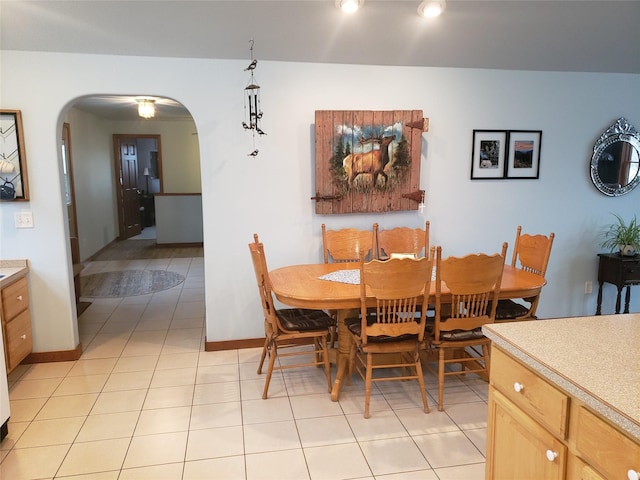 dining space featuring light tile patterned floors, baseboards, and arched walkways