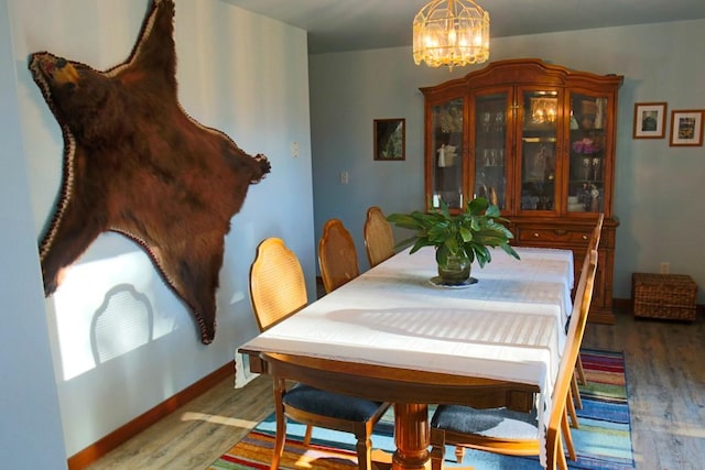 dining room with baseboards, wood finished floors, and a notable chandelier