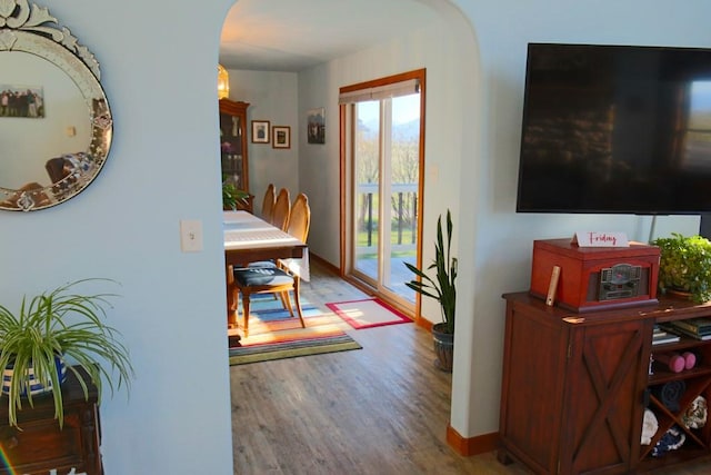 interior space with wood finished floors, baseboards, and arched walkways