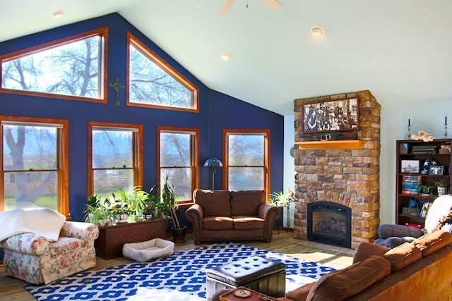 living room with a stone fireplace, wood finished floors, a ceiling fan, and vaulted ceiling