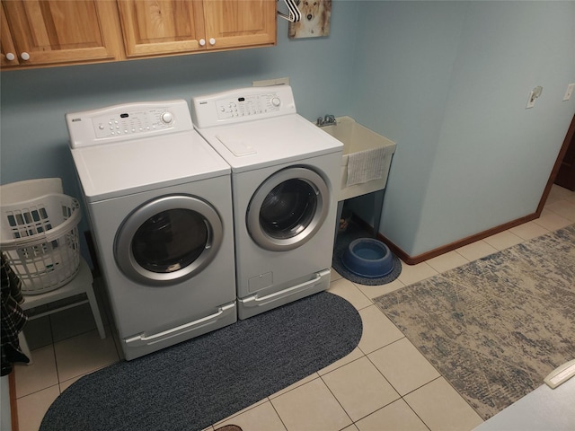 clothes washing area featuring baseboards, light tile patterned flooring, cabinet space, and washer and clothes dryer