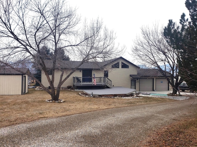 view of front facade with an attached garage, a front yard, an outdoor structure, driveway, and a wooden deck