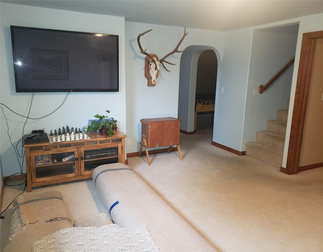 living room with carpet floors, stairway, baseboards, and arched walkways