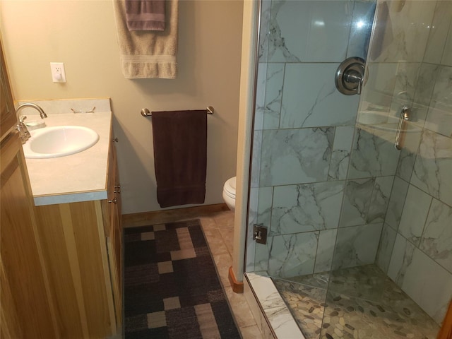 bathroom with toilet, a marble finish shower, and vanity
