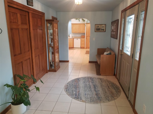 entrance foyer with baseboards, arched walkways, and light tile patterned flooring