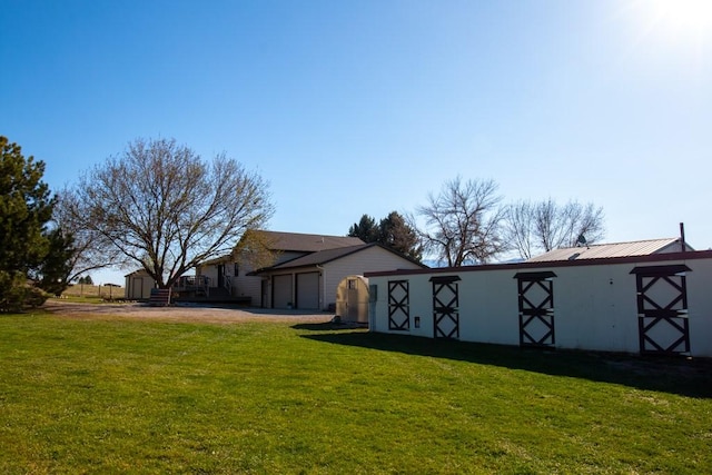 view of yard featuring an outbuilding, driveway, and an attached garage