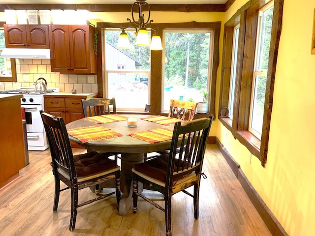 dining space with light wood-style floors, a notable chandelier, and baseboards