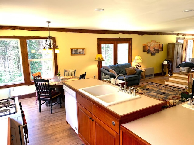 kitchen with light wood finished floors, gas stove, open floor plan, a sink, and dishwasher