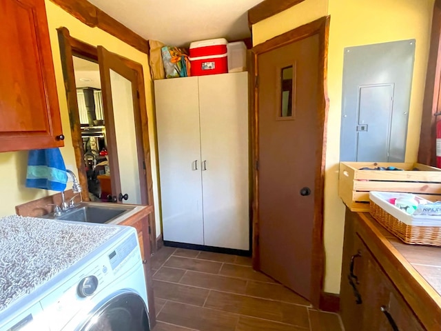 laundry area featuring cabinet space, electric panel, washer / clothes dryer, and a sink