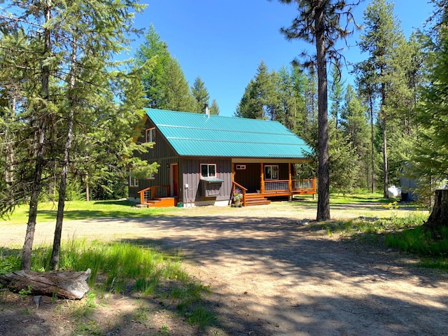 view of front of home with board and batten siding, metal roof, covered porch, and driveway