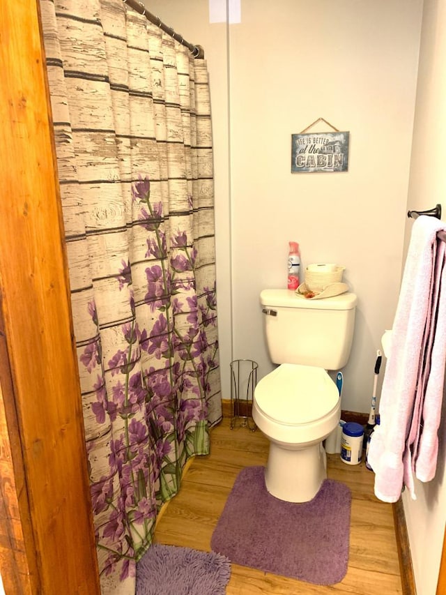 bathroom with a shower with curtain, baseboards, toilet, and wood finished floors