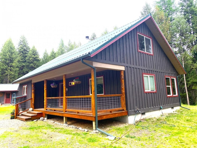 view of side of home featuring crawl space, covered porch, metal roof, and board and batten siding