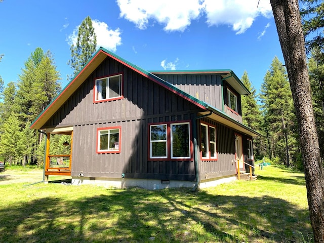 view of side of home with crawl space, a lawn, and board and batten siding