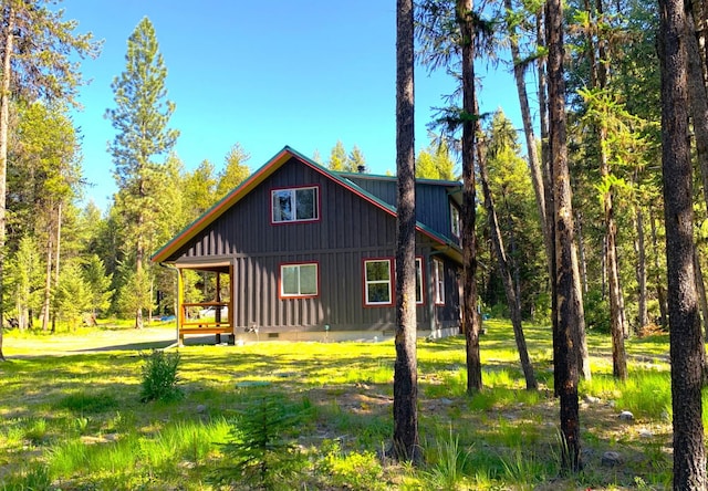 view of side of home with metal roof, a yard, and crawl space