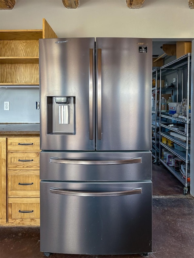 interior details featuring dark countertops, concrete floors, and stainless steel refrigerator with ice dispenser