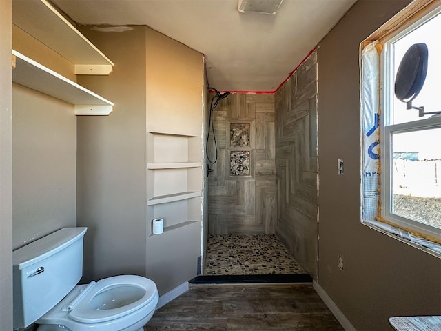 full bath with toilet, a stall shower, baseboards, and wood finished floors