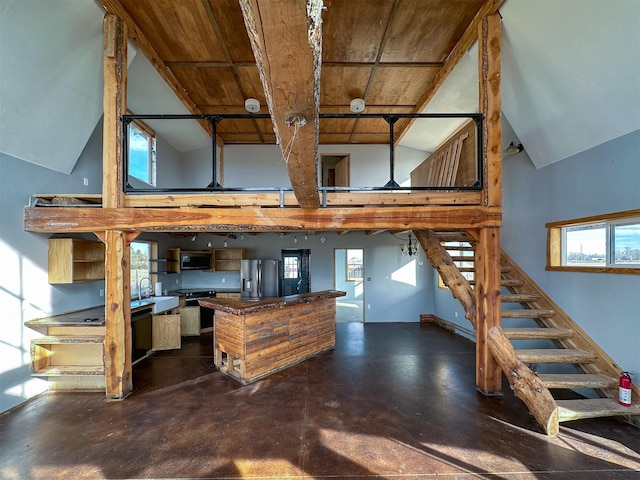 kitchen with appliances with stainless steel finishes, concrete floors, high vaulted ceiling, and baseboards