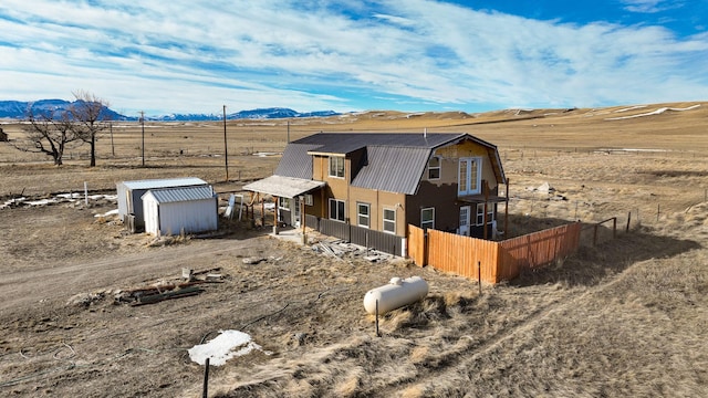 view of front facade featuring an outbuilding, fence, a mountain view, and a gambrel roof