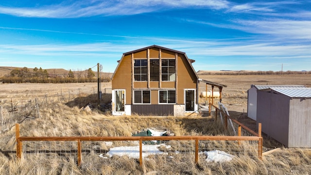 rear view of house featuring fence and an outdoor structure