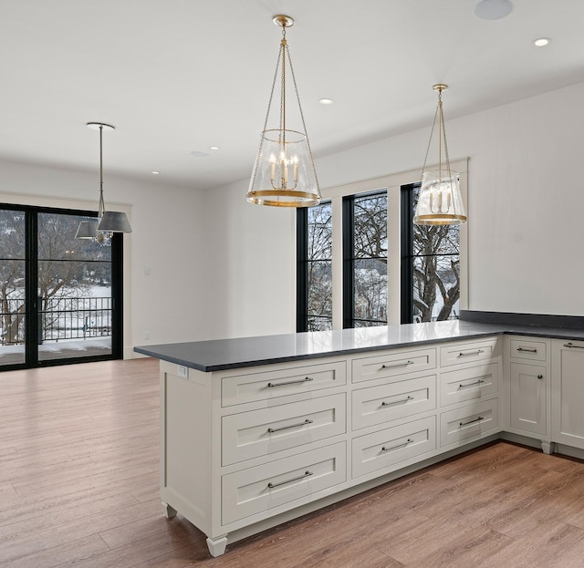 kitchen with light wood-style floors, recessed lighting, hanging light fixtures, and dark countertops