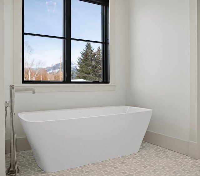 bathroom with a soaking tub and baseboards