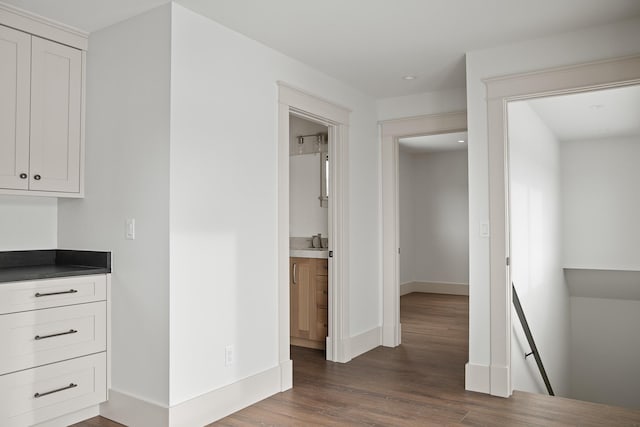 interior space featuring dark wood-type flooring, an upstairs landing, a sink, and baseboards