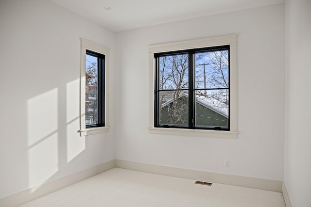 spare room featuring carpet floors, baseboards, and visible vents