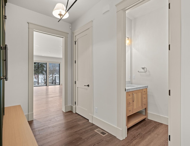 hallway with dark wood-style flooring, visible vents, and baseboards