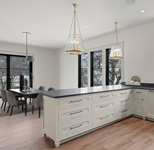 kitchen featuring dark countertops, light wood-style floors, and decorative light fixtures