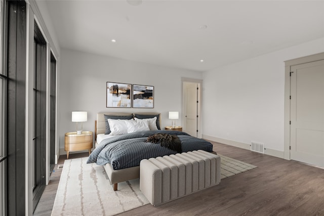 bedroom featuring visible vents, baseboards, and wood finished floors