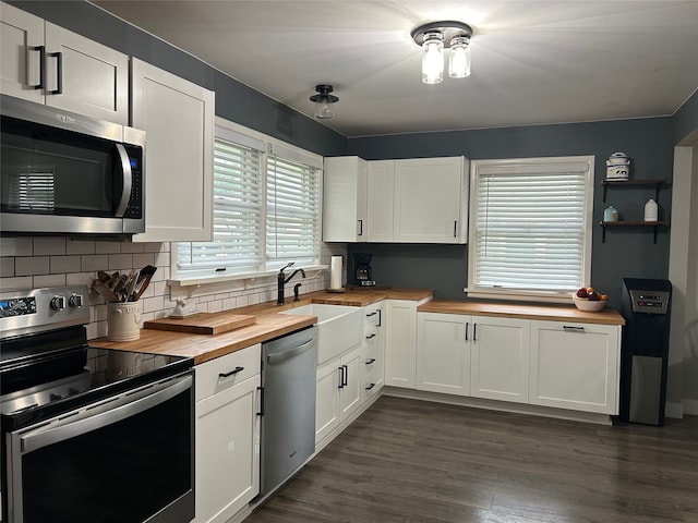 kitchen with dark wood-style floors, stainless steel appliances, tasteful backsplash, butcher block counters, and white cabinetry