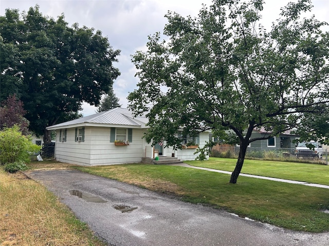 ranch-style home with a front yard, metal roof, and fence