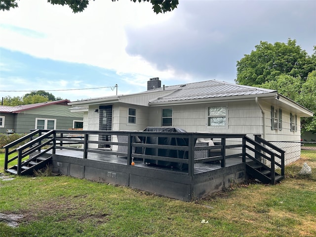 back of house featuring central AC unit, a chimney, metal roof, a deck, and a yard