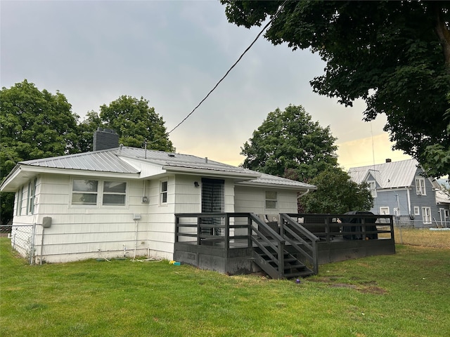 view of front of property featuring metal roof, a front lawn, a chimney, and fence