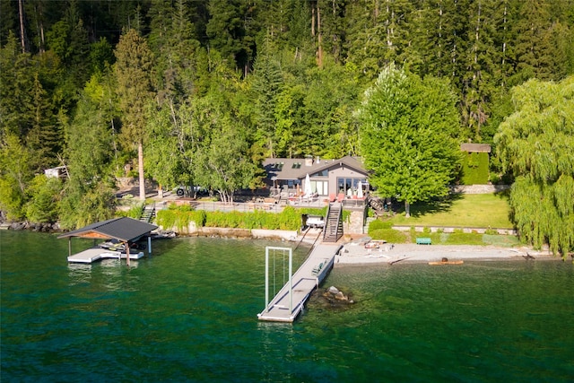 view of dock with a water view, a forest view, and stairs