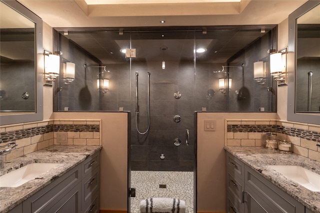 bathroom with tasteful backsplash, two vanities, a sink, and tiled shower