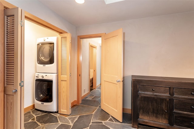 washroom with stacked washer and dryer, laundry area, and baseboards