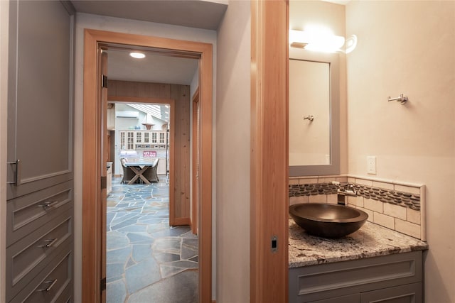 bathroom featuring decorative backsplash, vanity, and stone tile floors