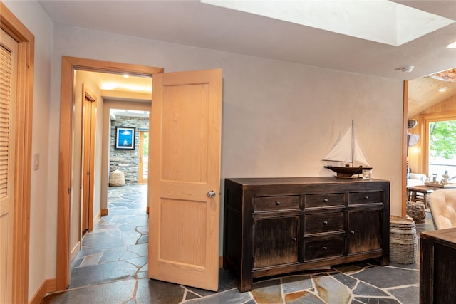 hallway featuring stone tile floors and baseboards