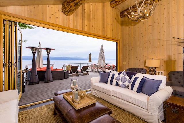 living room featuring a water view, an inviting chandelier, a wealth of natural light, and beam ceiling