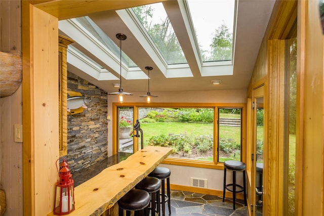 interior space with lofted ceiling, stone finish flooring, visible vents, and baseboards