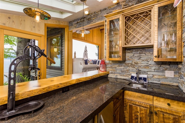 bar featuring wet bar, pendant lighting, a sink, and wooden walls