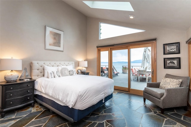 bedroom featuring lofted ceiling with skylight, access to exterior, stone tile flooring, and a mountain view