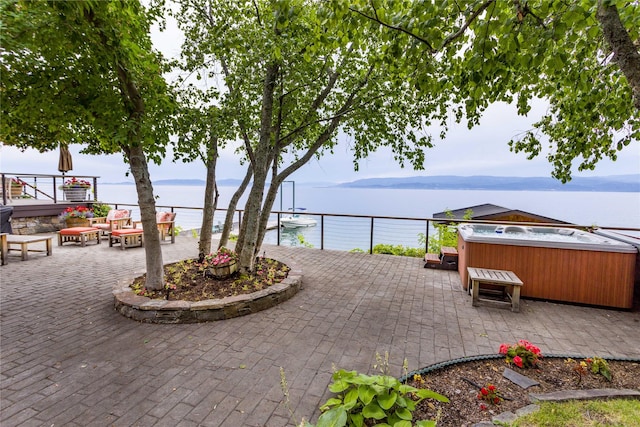 view of patio featuring a water view and a hot tub